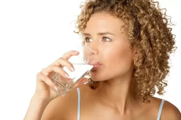 The girl follows a lazy diet, drinking a glass of water before eating